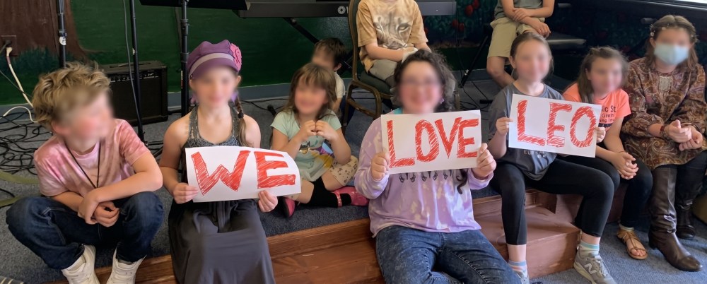 Students holding up signs that say "WE LOVE LEO".